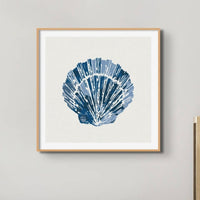 Set of three coastal shell prints above a white sofa in a beachy living room