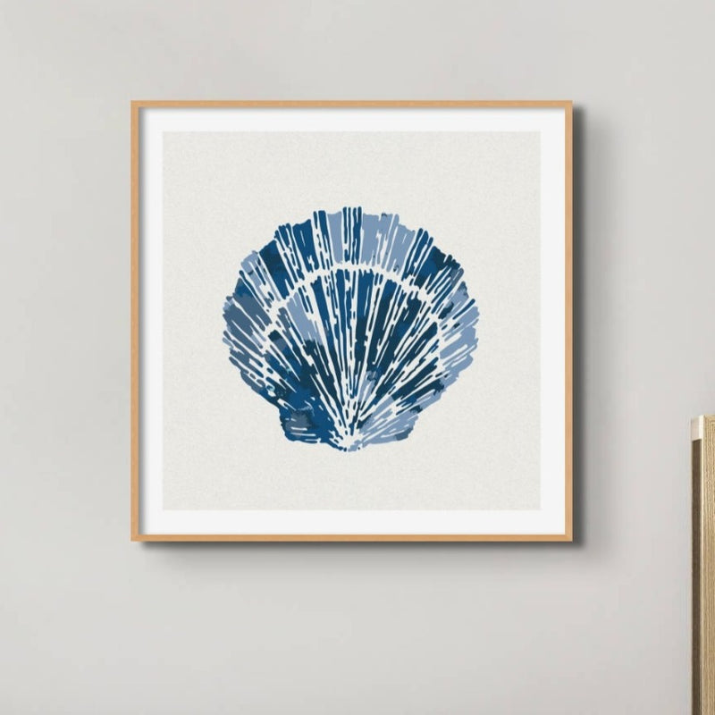 Set of three coastal shell prints above a white sofa in a beachy living room