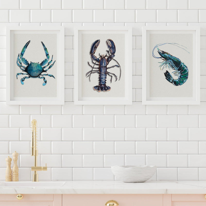 Kitchen with pink cabinets and white subway tile backsplash, showcasing three framed art prints of a lobster, crab, and prawn, adding a stylish touch to the culinary space.