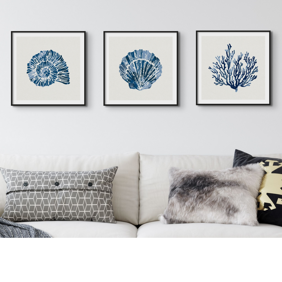 Set of three coastal shell prints above a white sofa in a beachy living room