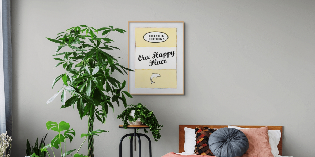 framed yellow art print on wall in bedroom - yellow book cover print wiht our happy place typography