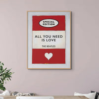 Vintage red book cover with All You Need is Love as the title by the Beatles hanging on a pink wall above a white sideboard- Beach House Art