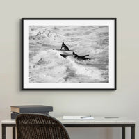 black & white photograph of two surfers in the surf in a black frame above a desk - beach house art