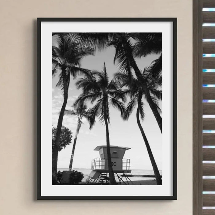 black & white beach art photograph of a life savers lookout in a palm tree grove in a black frame in a kitchen with dark shutters- beach house art