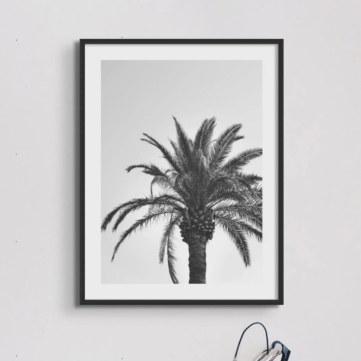 black & white palm tree wall art - photograph of a palm tree against a grey sky above a bicycle leaning against the wall - beach house art