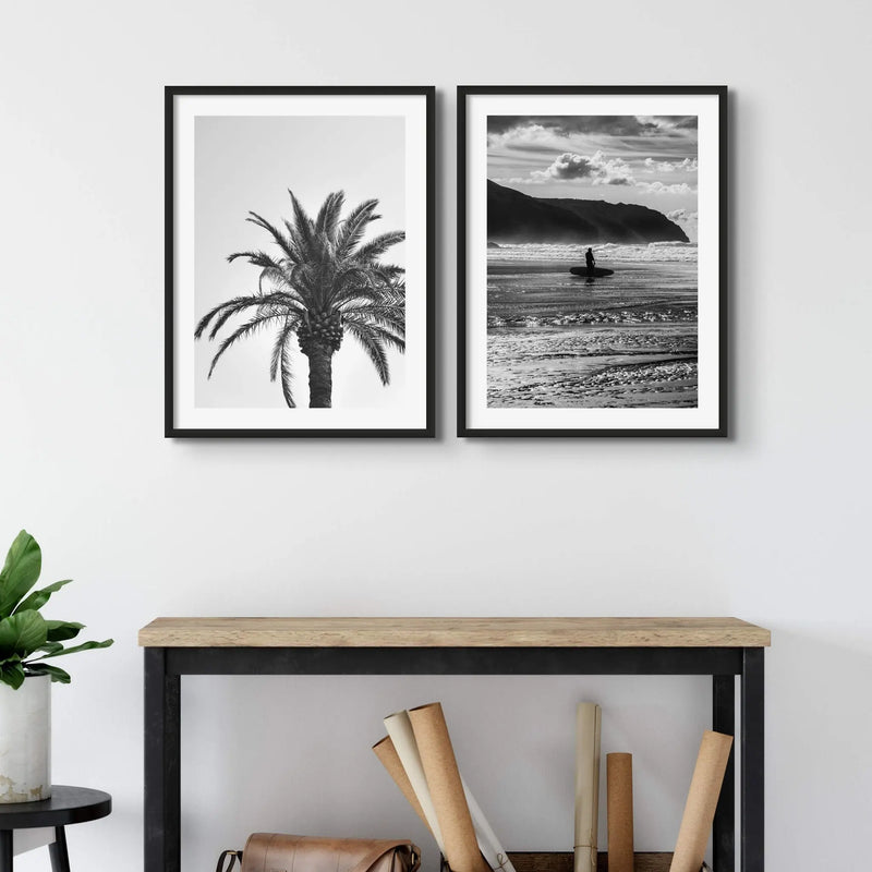 set of two black & white photographs of a palm tree and a surfer above a side board - beach house art