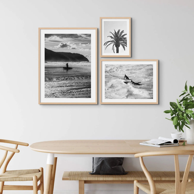 set of three black and white beach art photographs in a light coloured wood dining room
