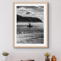 black & white beach art photograph of a solitary surfer walking into the waves framed above a small desk - beach house art