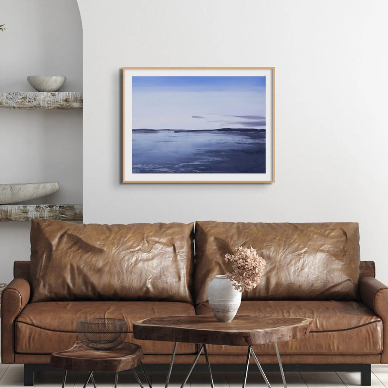 a painted seascape of a sunrise above Padstow above a brown leather sofa - beach house art